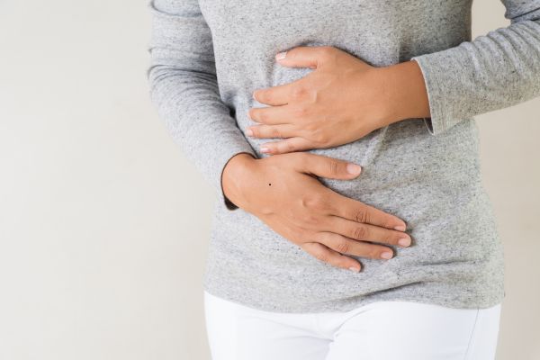 A woman holds her stomach due to pain.