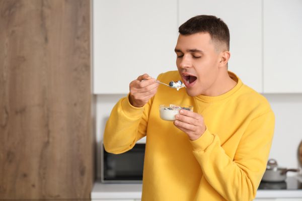 A man eating yogurt to improve gut health.